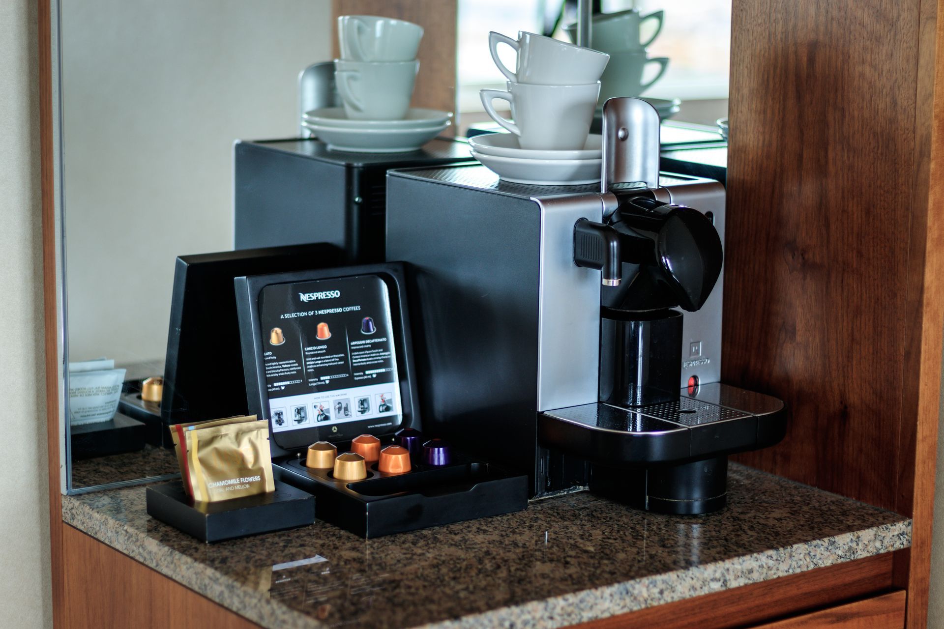 A coffee machine is sitting on a counter next to a mirror.