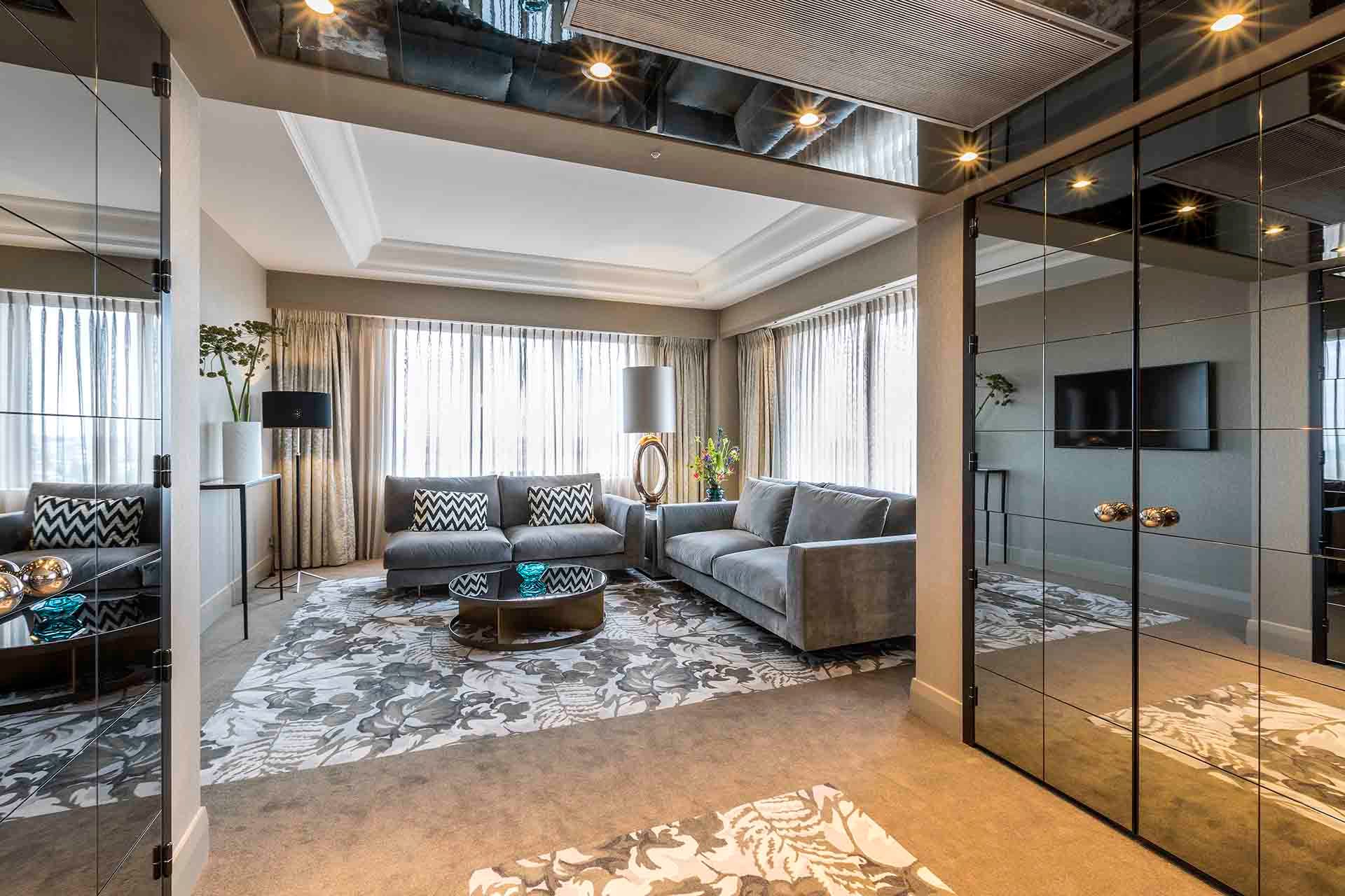 A living room with a couch , coffee table , and mirrored walls.