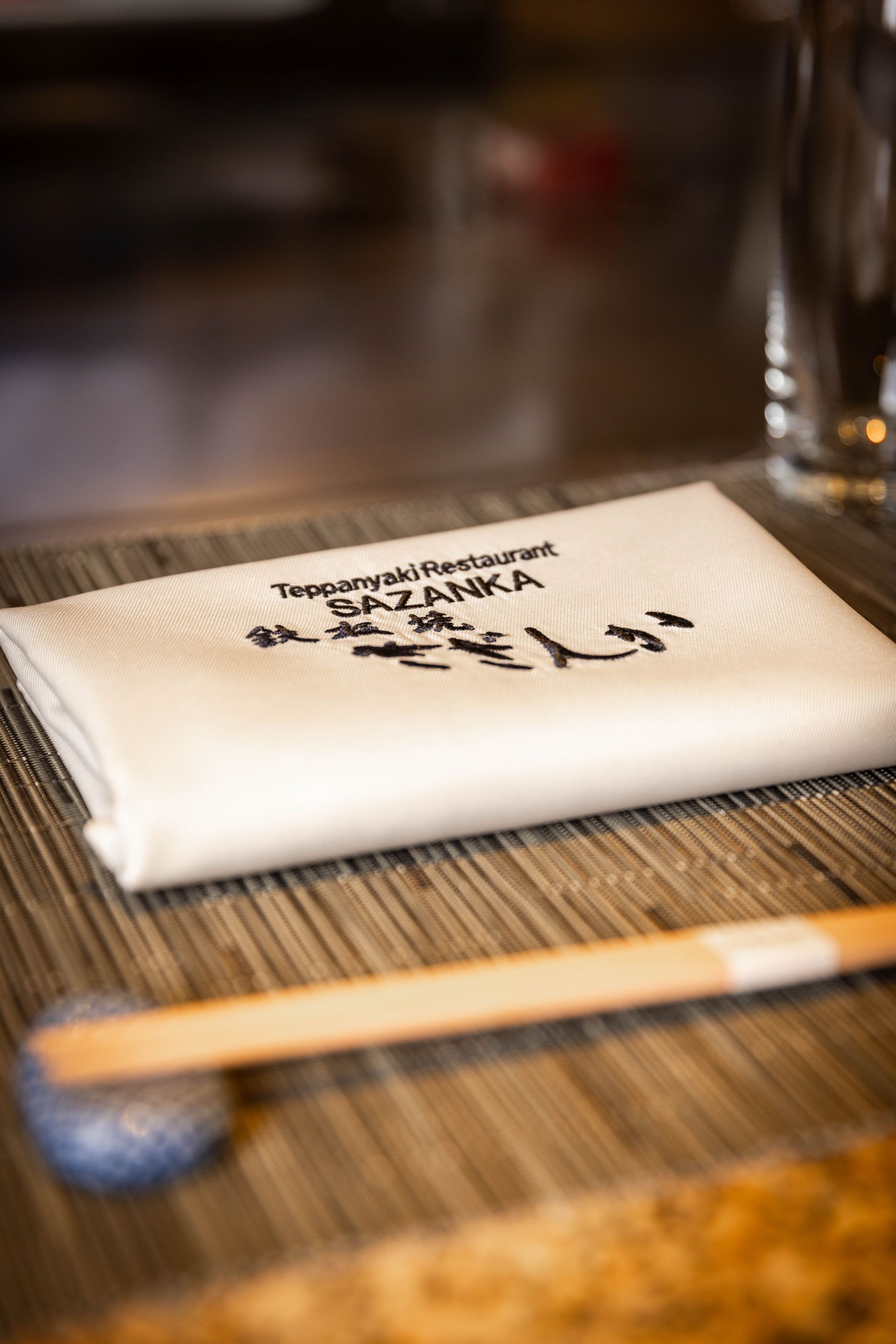 A napkin with chopsticks and a glass of water on a table.