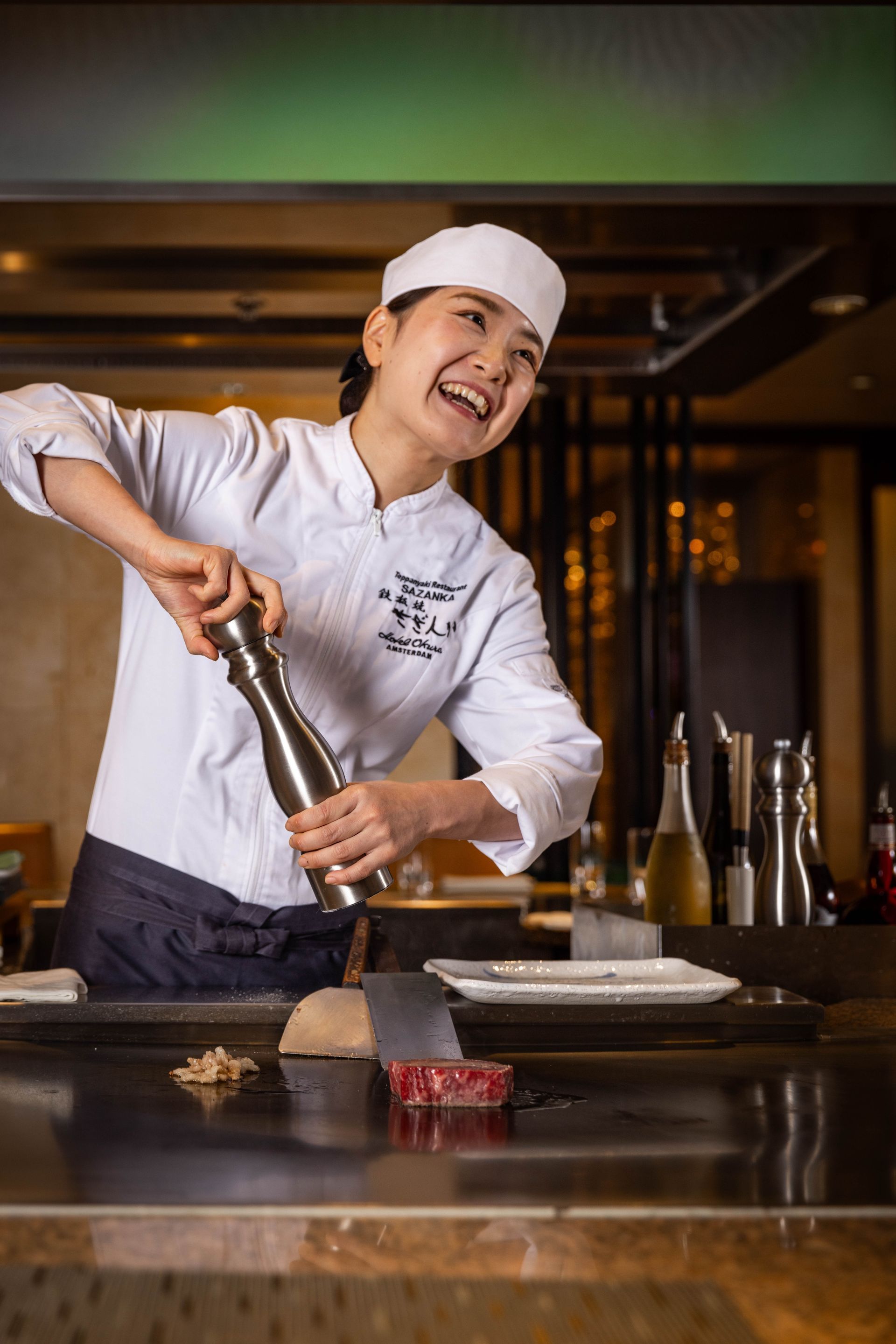 A woman in a chef 's uniform is preparing food in a restaurant.