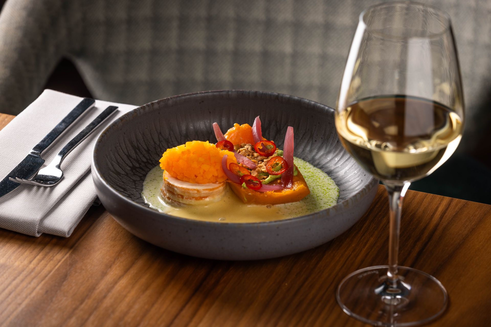 A plate of food and a glass of wine on a wooden table.