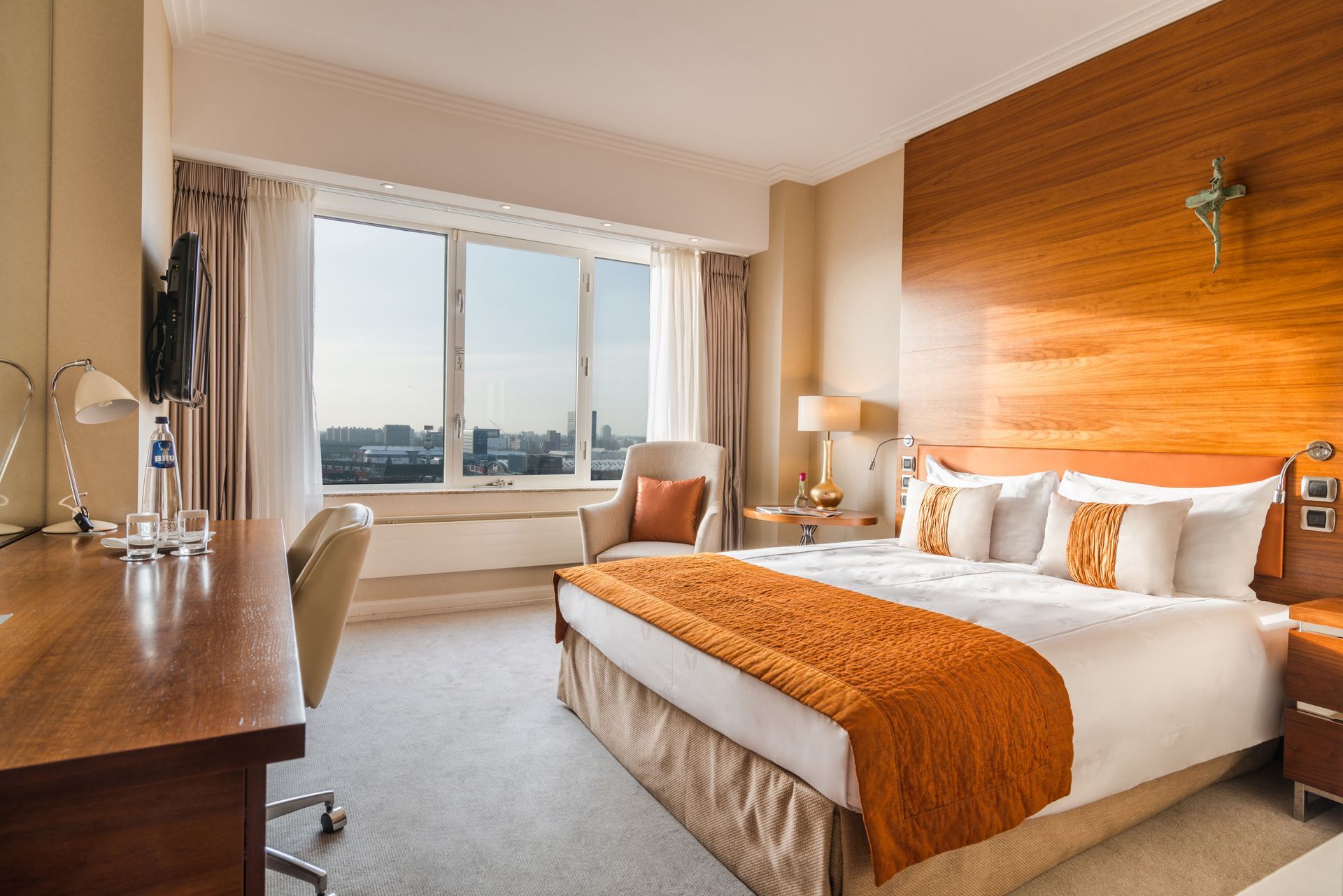 A hotel room with a large bed , desk , chair and large window.