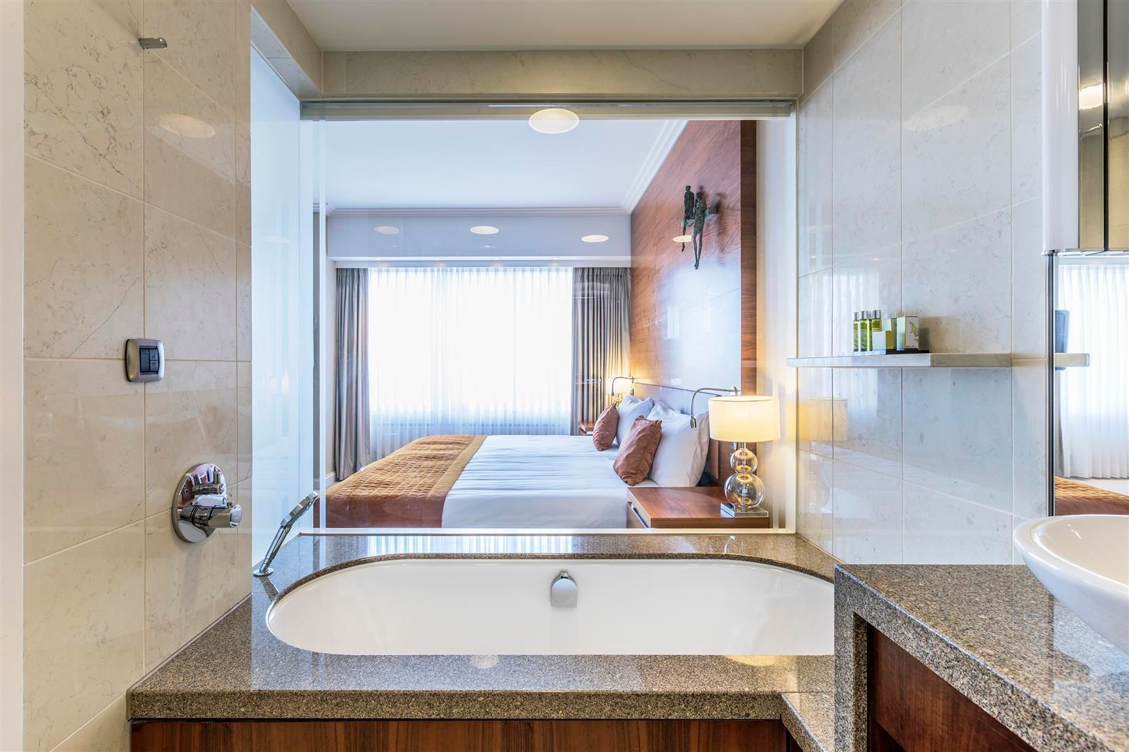A hotel room with a bathtub and a bed.