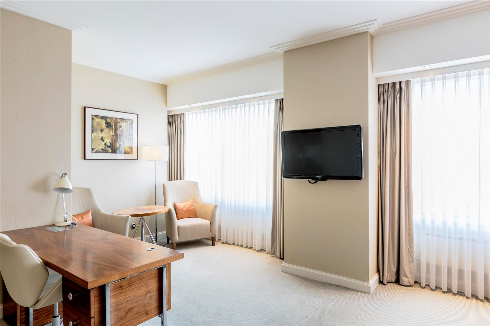 A hotel room with a desk , chair and television.