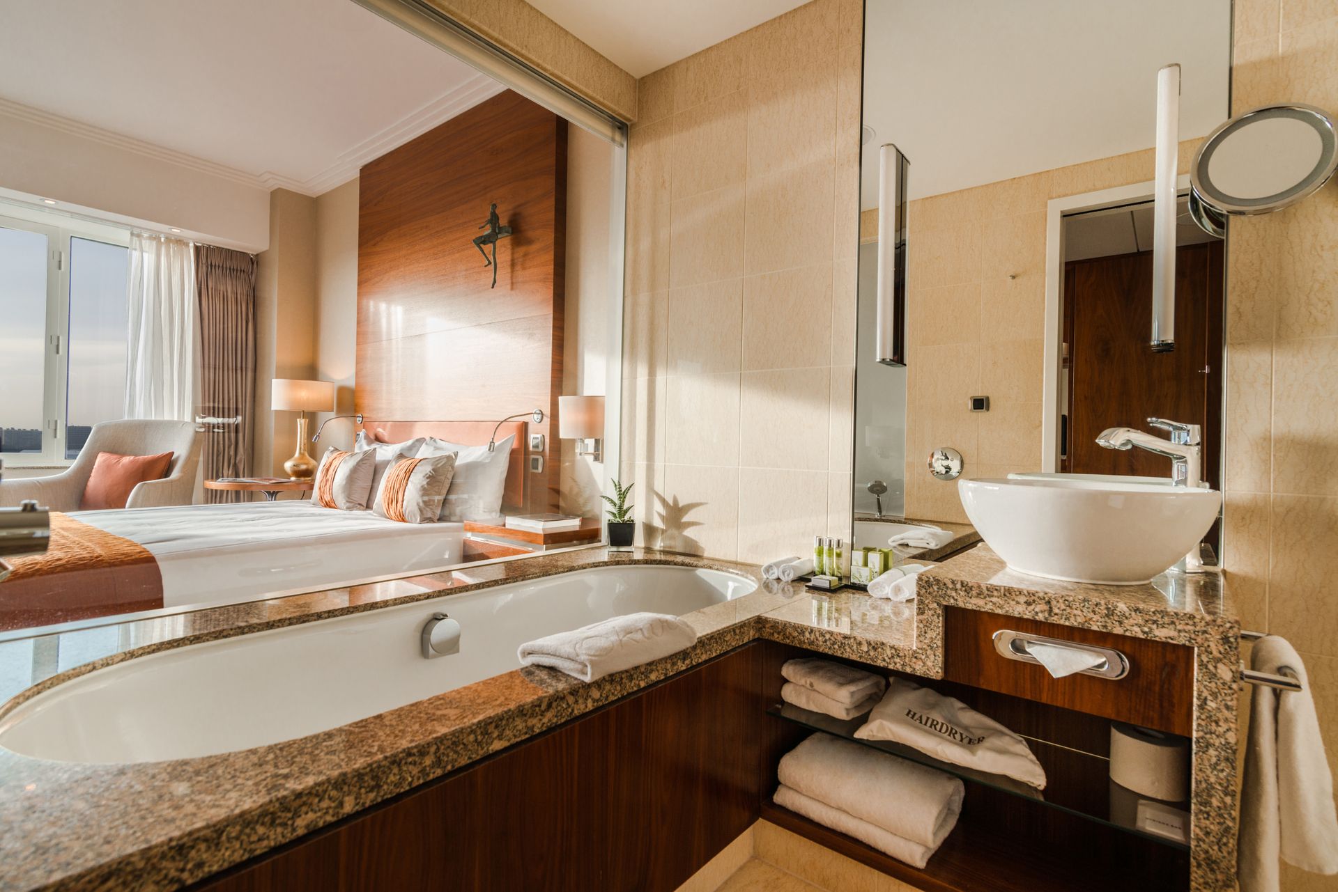 A hotel room with a bathtub , sink , mirror and bed.