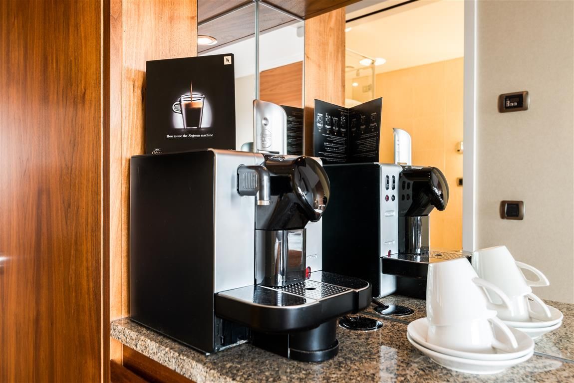 A coffee machine is sitting on a counter next to cups and saucers.