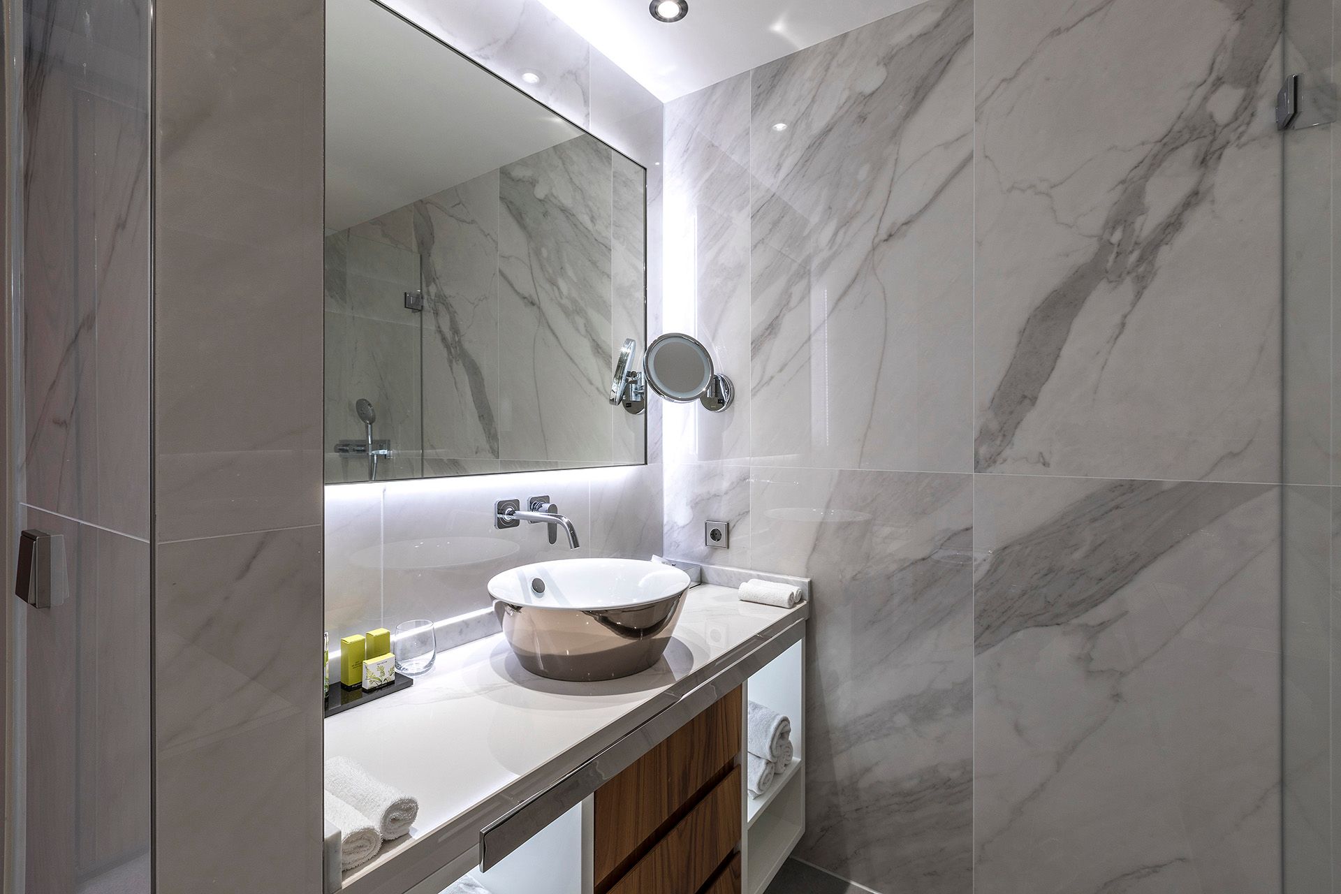 A bathroom with a sink , mirror and shower.