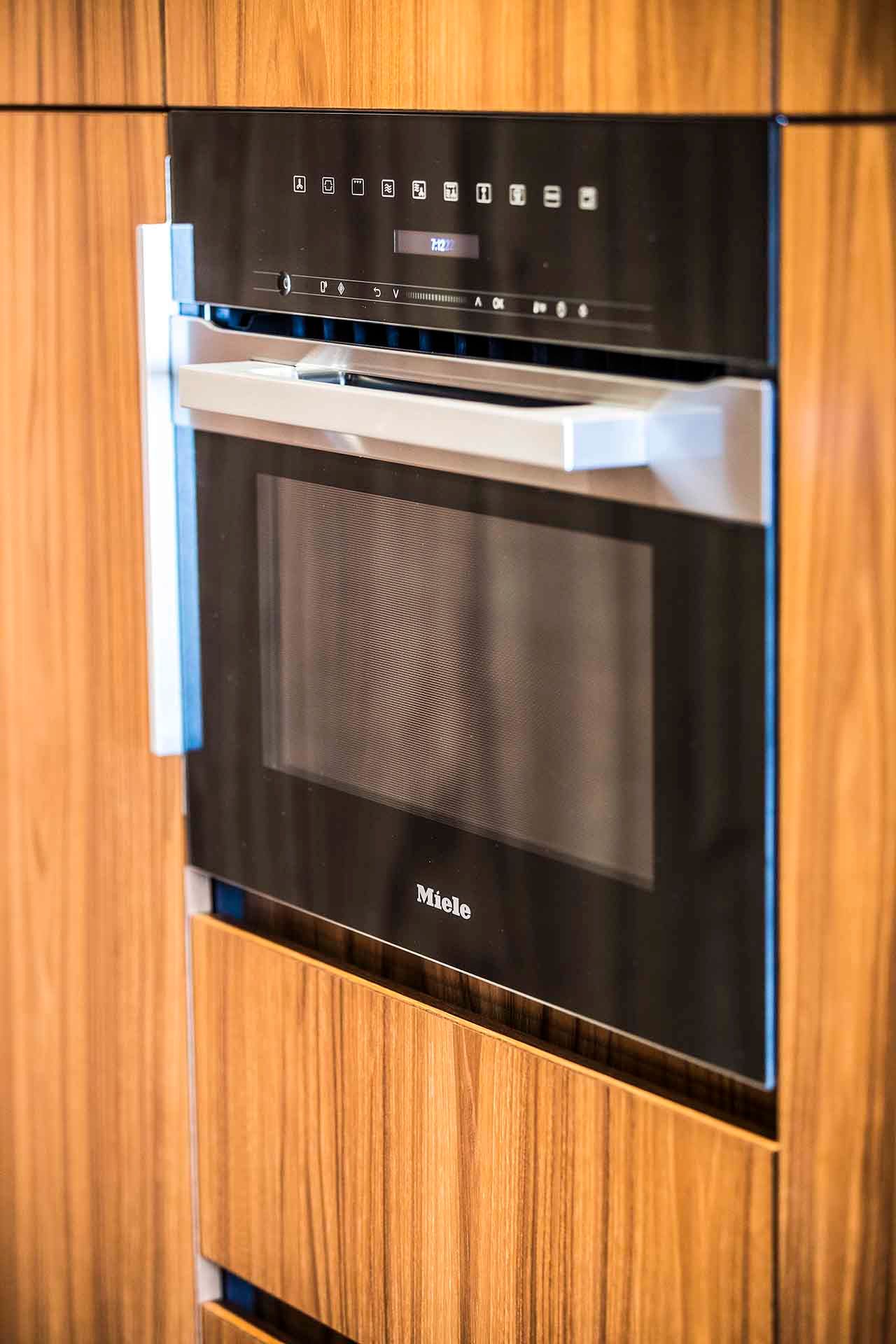 A black microwave oven is built into a wooden cabinet.