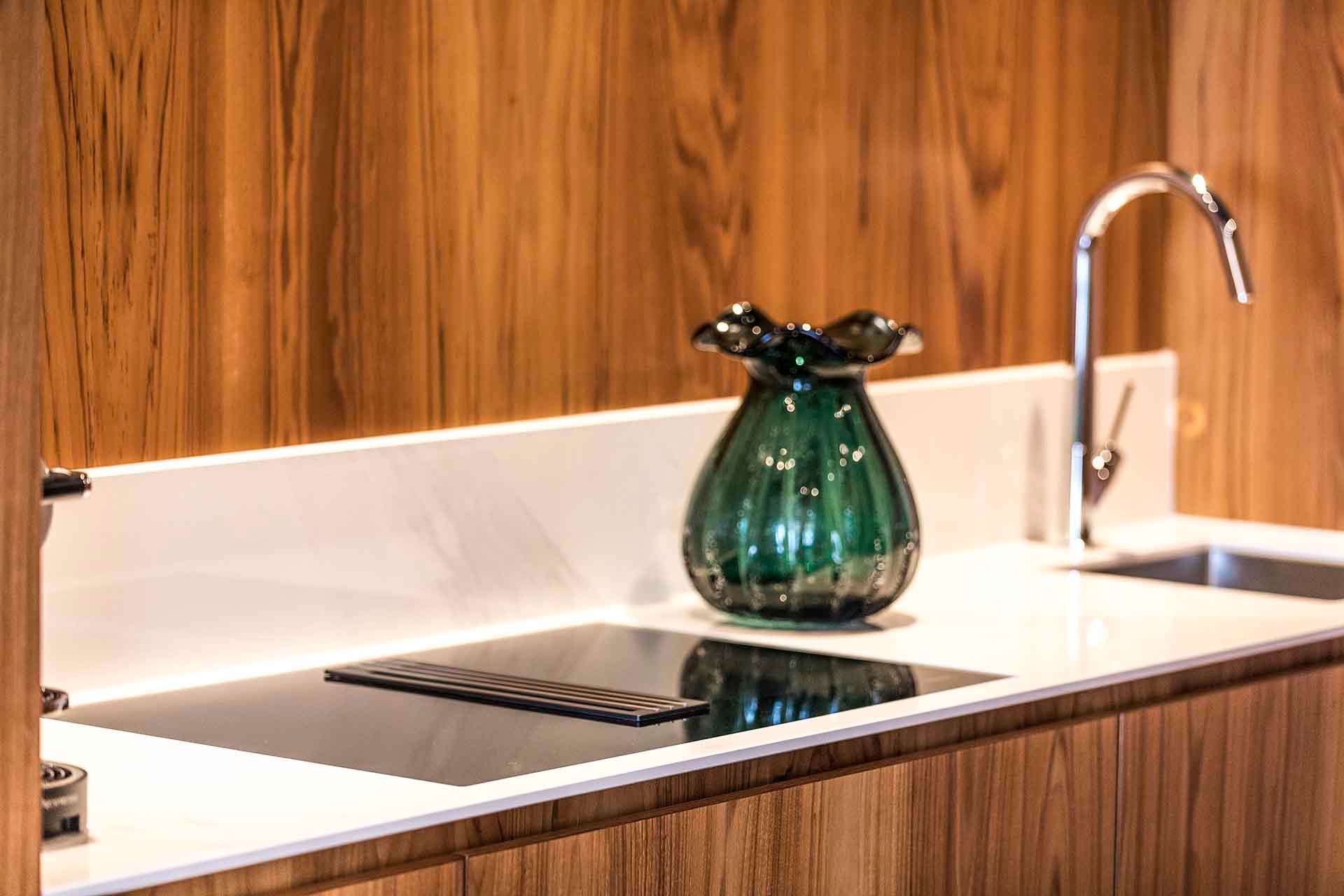 A green vase is sitting on a kitchen counter next to a sink.