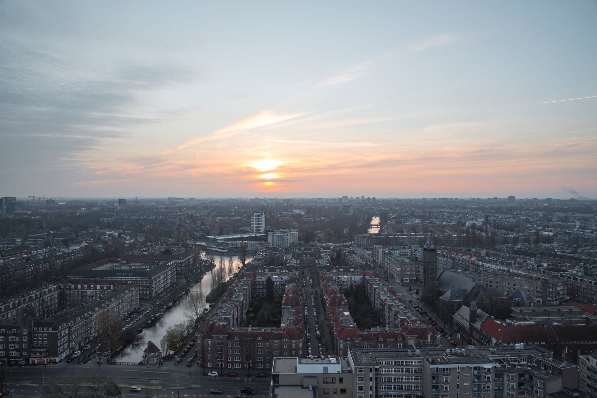 An aerial view of a city at sunset with a river in the foreground.