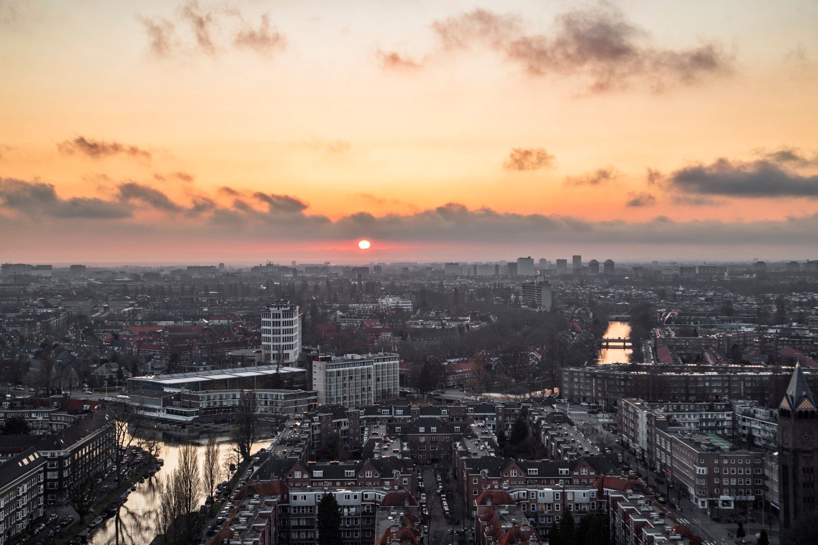 An aerial view of a city at sunset with a river in the foreground.