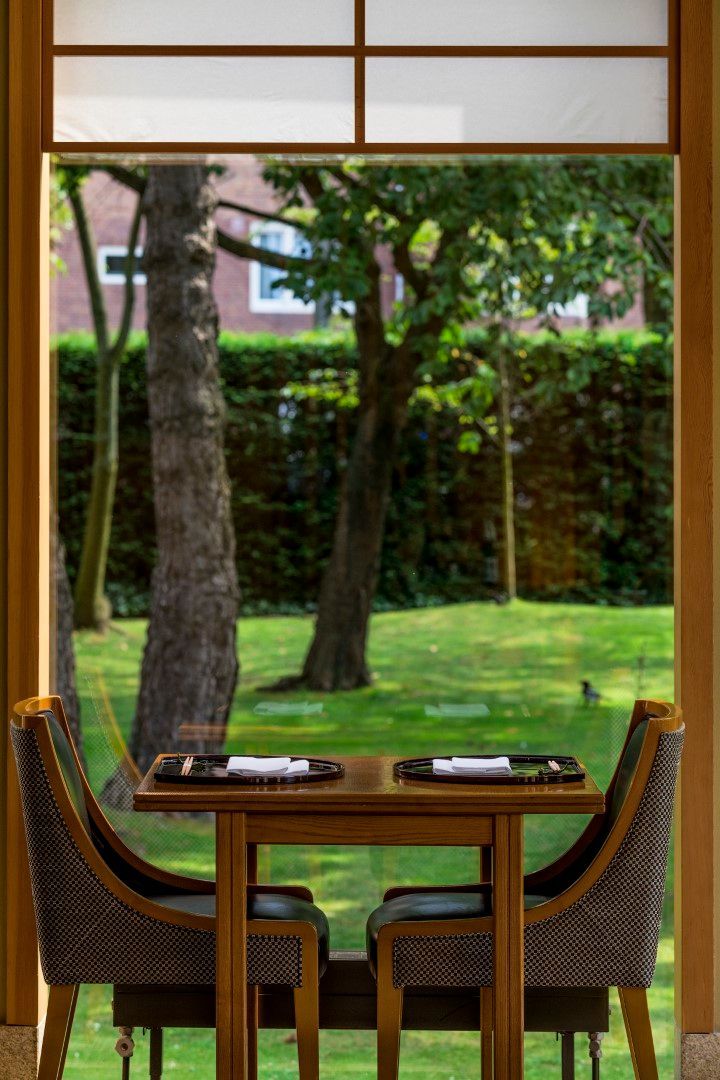 A table and chairs in front of a window overlooking a lush green field.