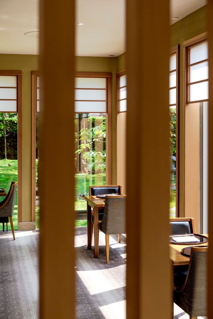 A dining room with tables and chairs and a fence between the tables and chairs.