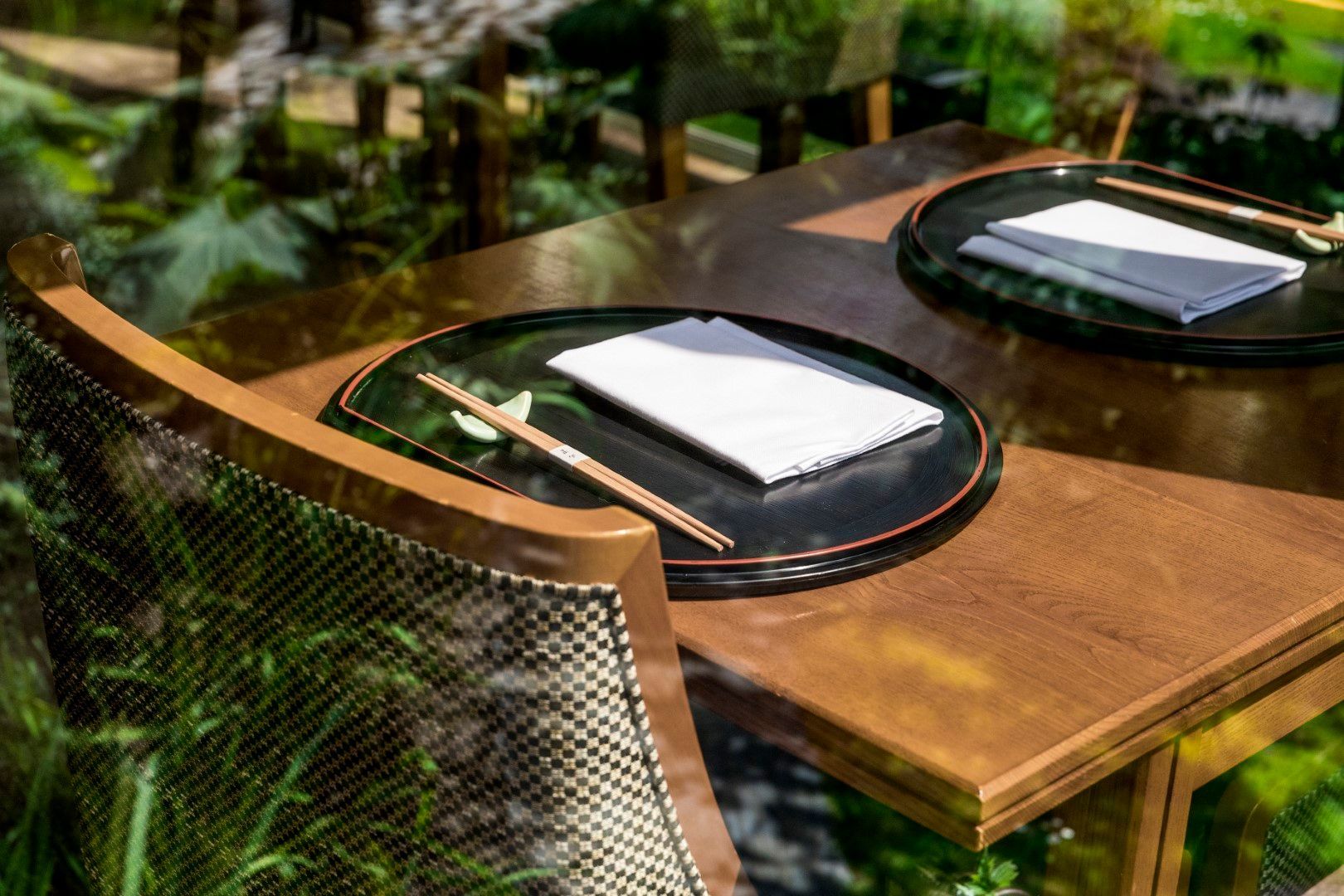 A wooden table with chopsticks and a napkin on it.