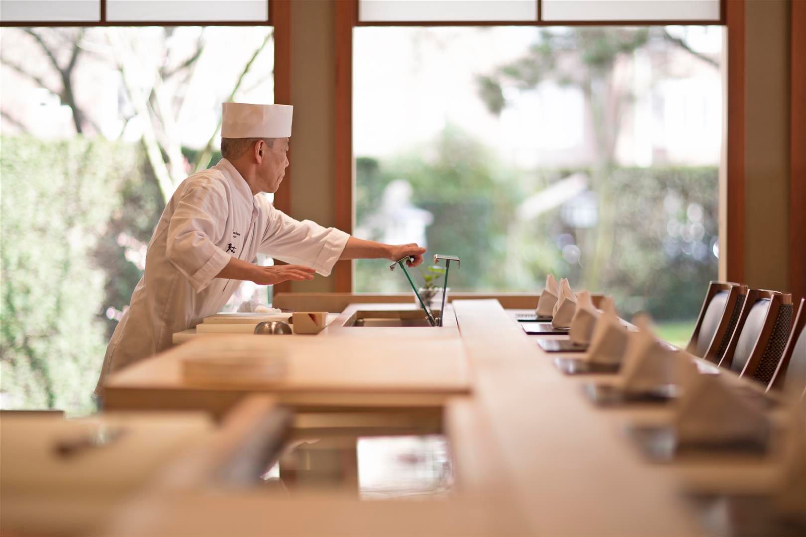 A chef is standing at a counter in a restaurant.