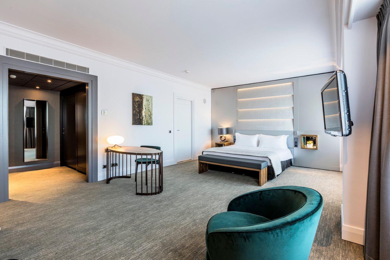 A hotel room with a bed , chair , desk and television.