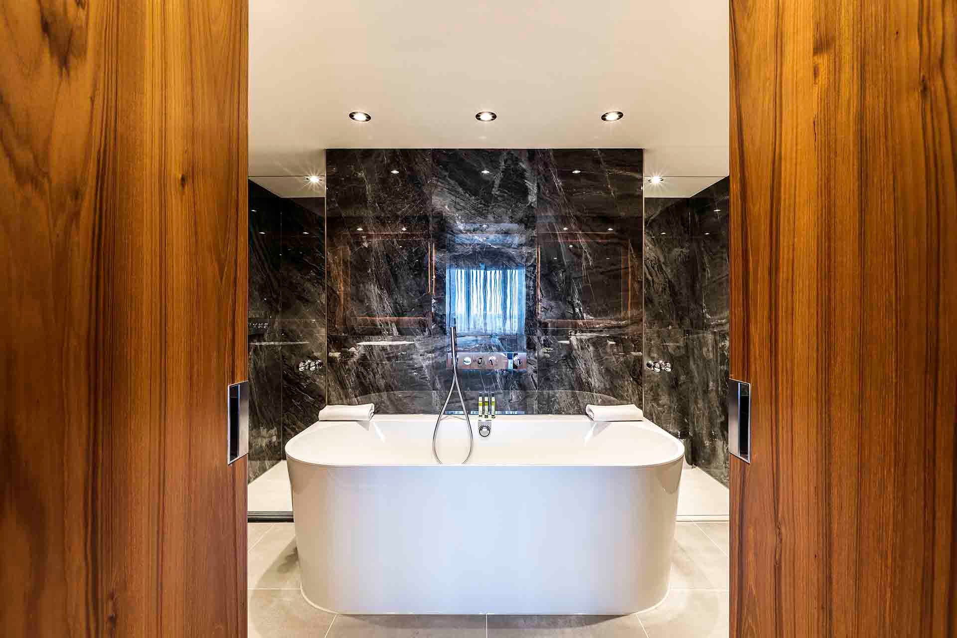 A bathroom with a bathtub and a television on the wall.