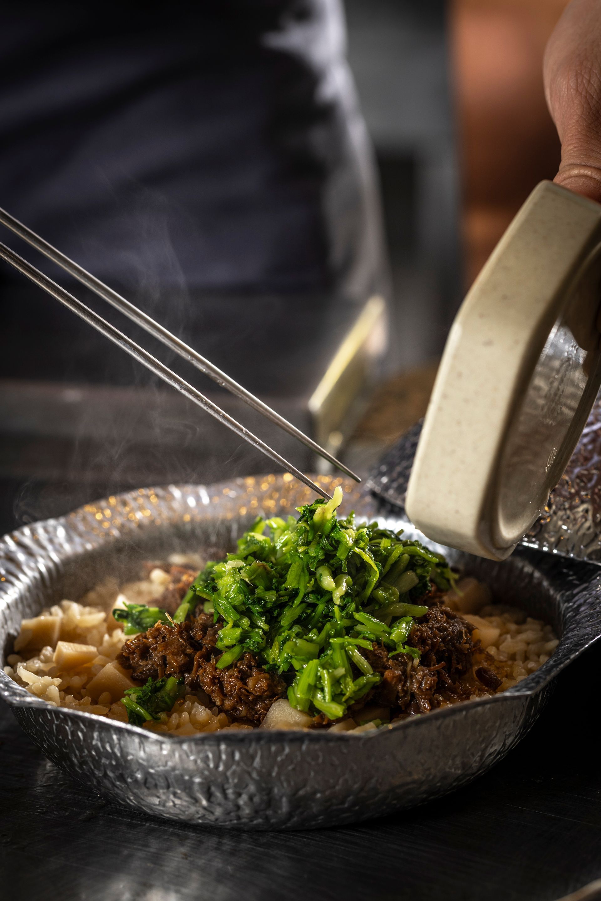A chef is standing in a kitchen with his arms crossed.