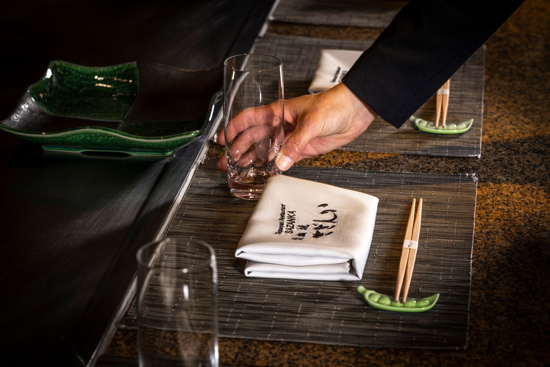 A napkin with chopsticks and a glass of water on a table.