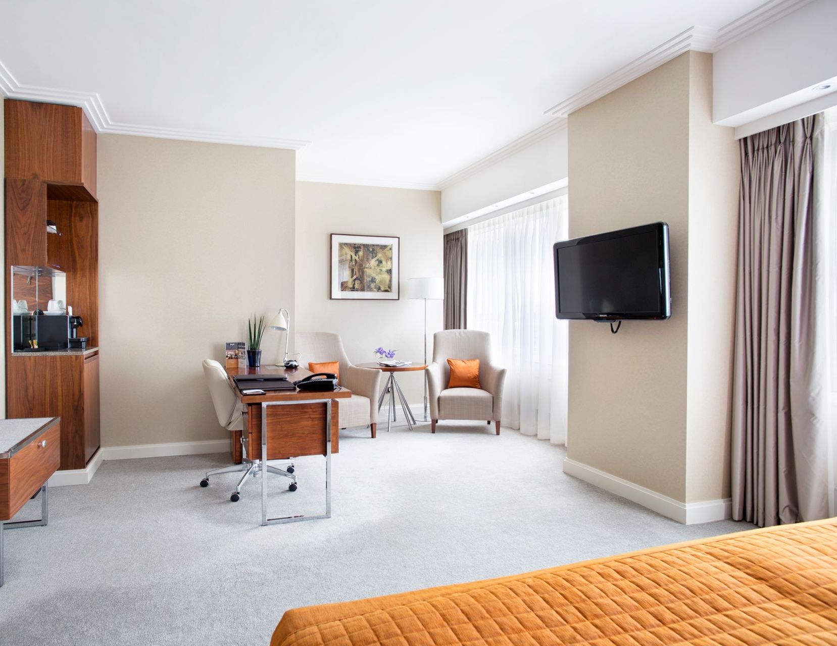 A hotel room with a large bed , desk , chairs and television.