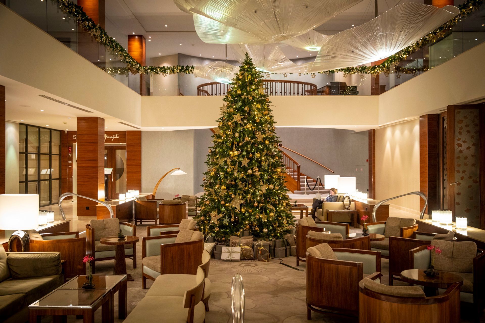 A large christmas tree is in the middle of a hotel lobby.