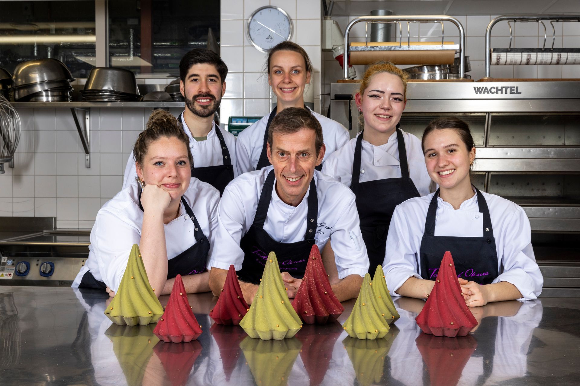 A group of chefs are posing for a picture in a kitchen.