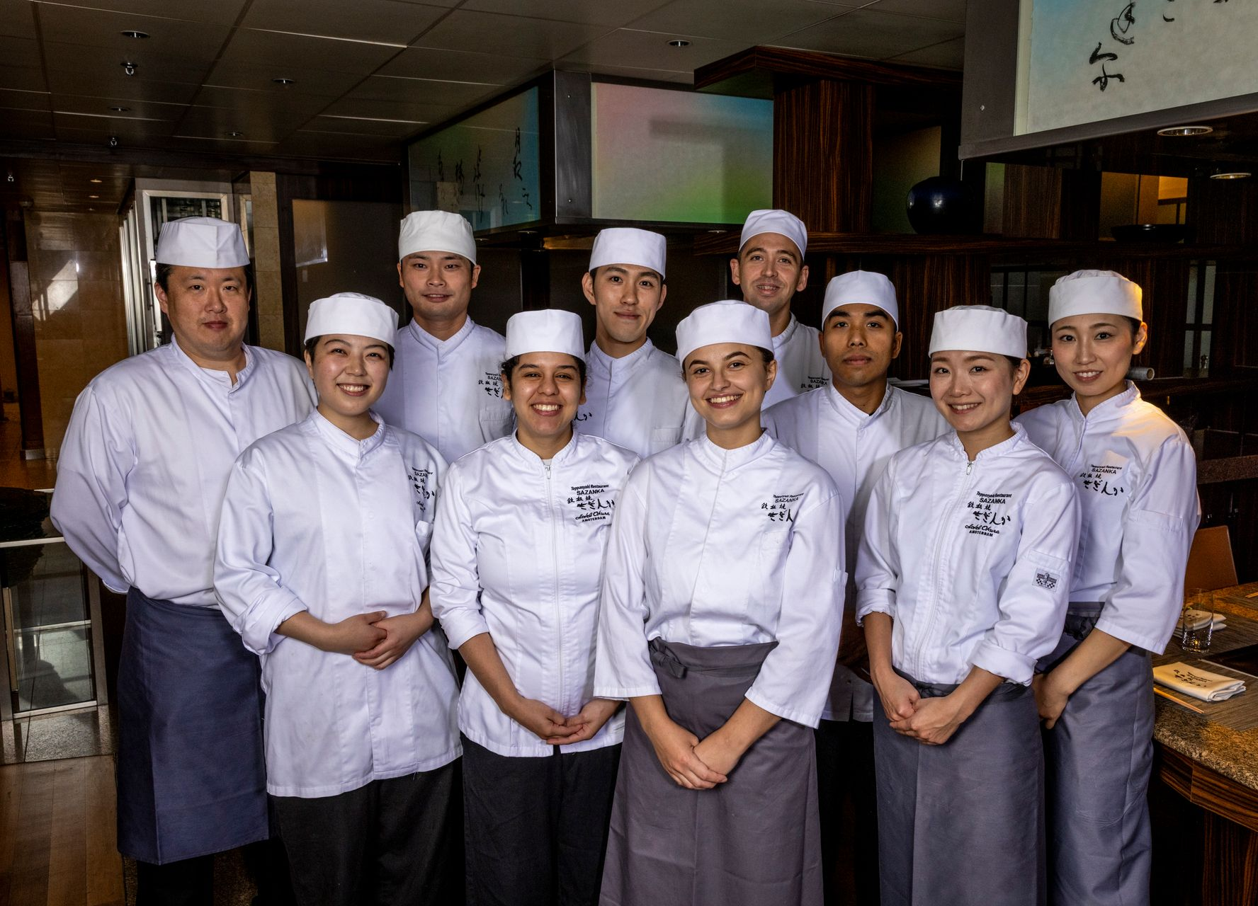 A group of chefs are posing for a picture in a restaurant.