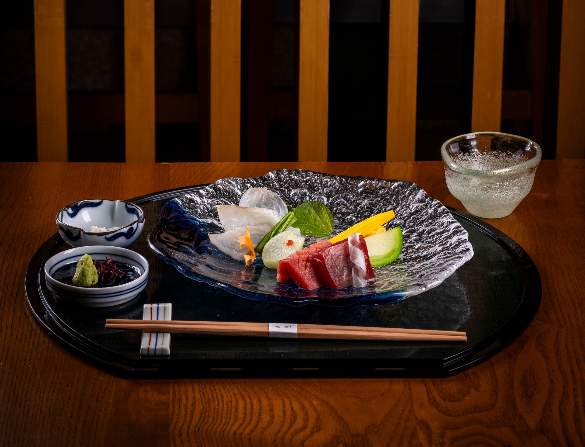 Sashimi platter with tuna, white fish, and avocado. Served with soy sauce, wasabi, and sake in a restaurant.