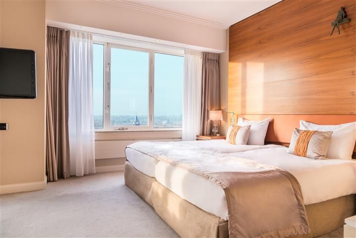 A hotel room with two beds , a television and a large window.