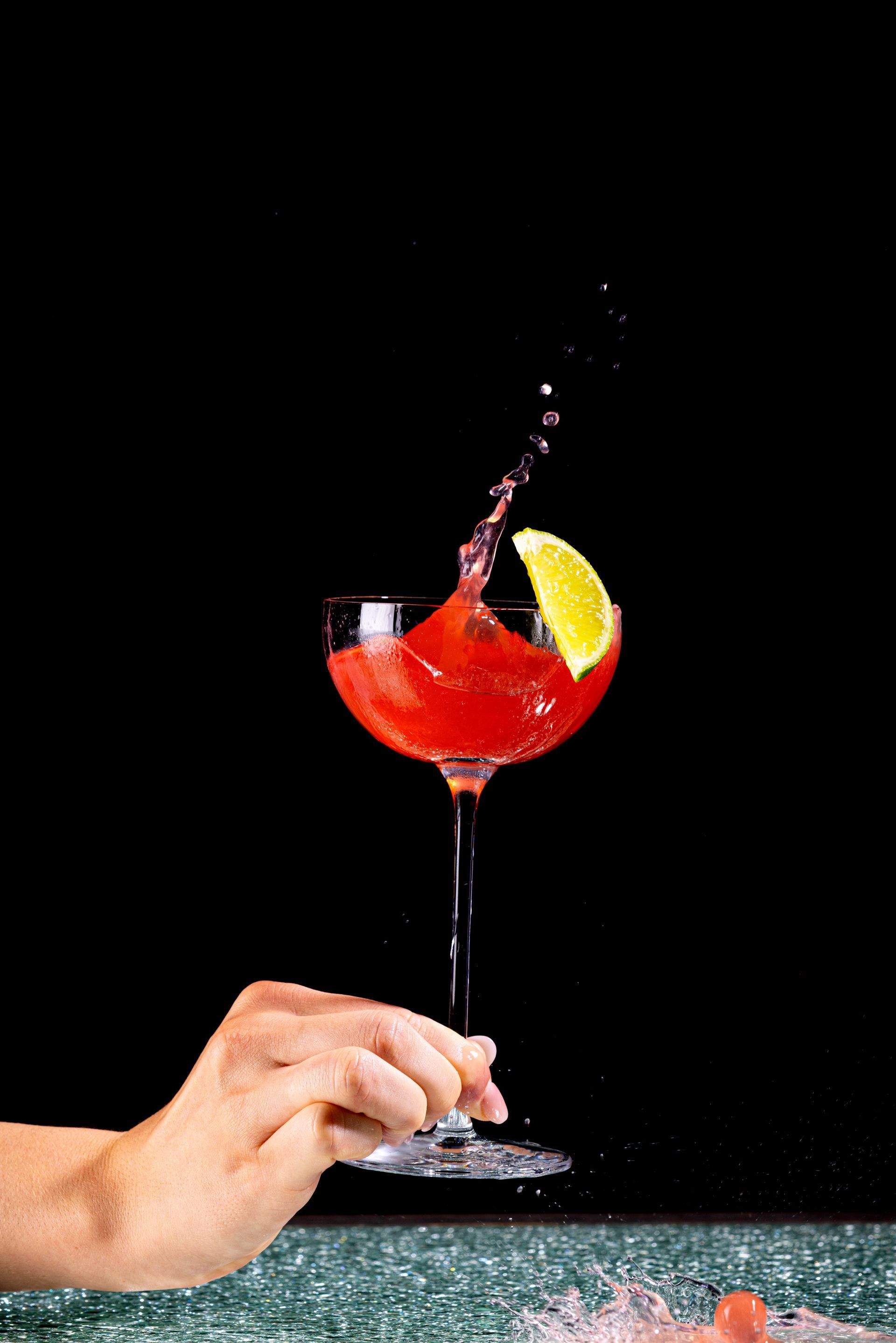 A woman is holding a gold coin over a glass of ice.