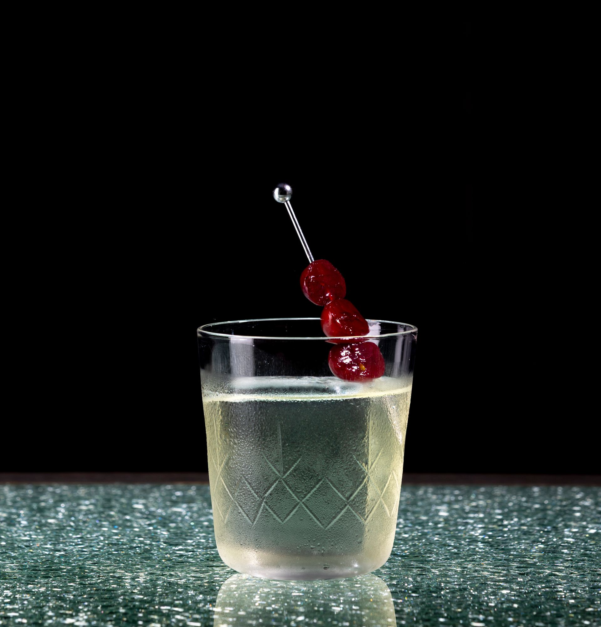 A bartender is adding a flower to a cocktail in a coupe glass.