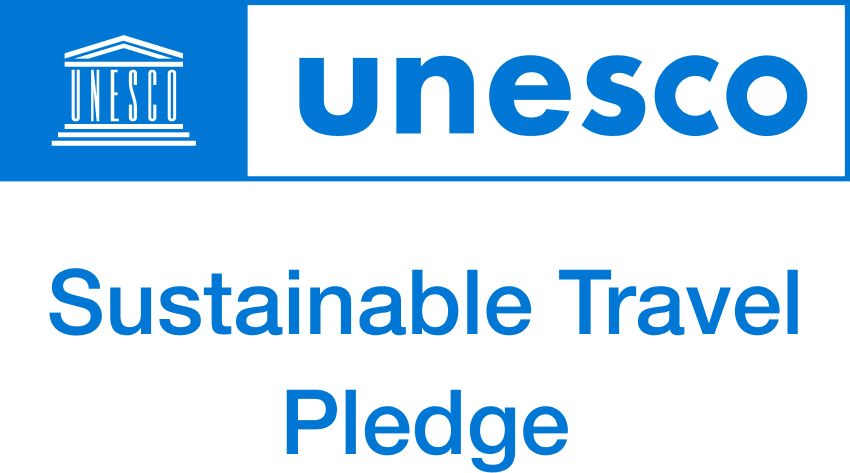 A blue and white logo for unesco sustainable travel pledge