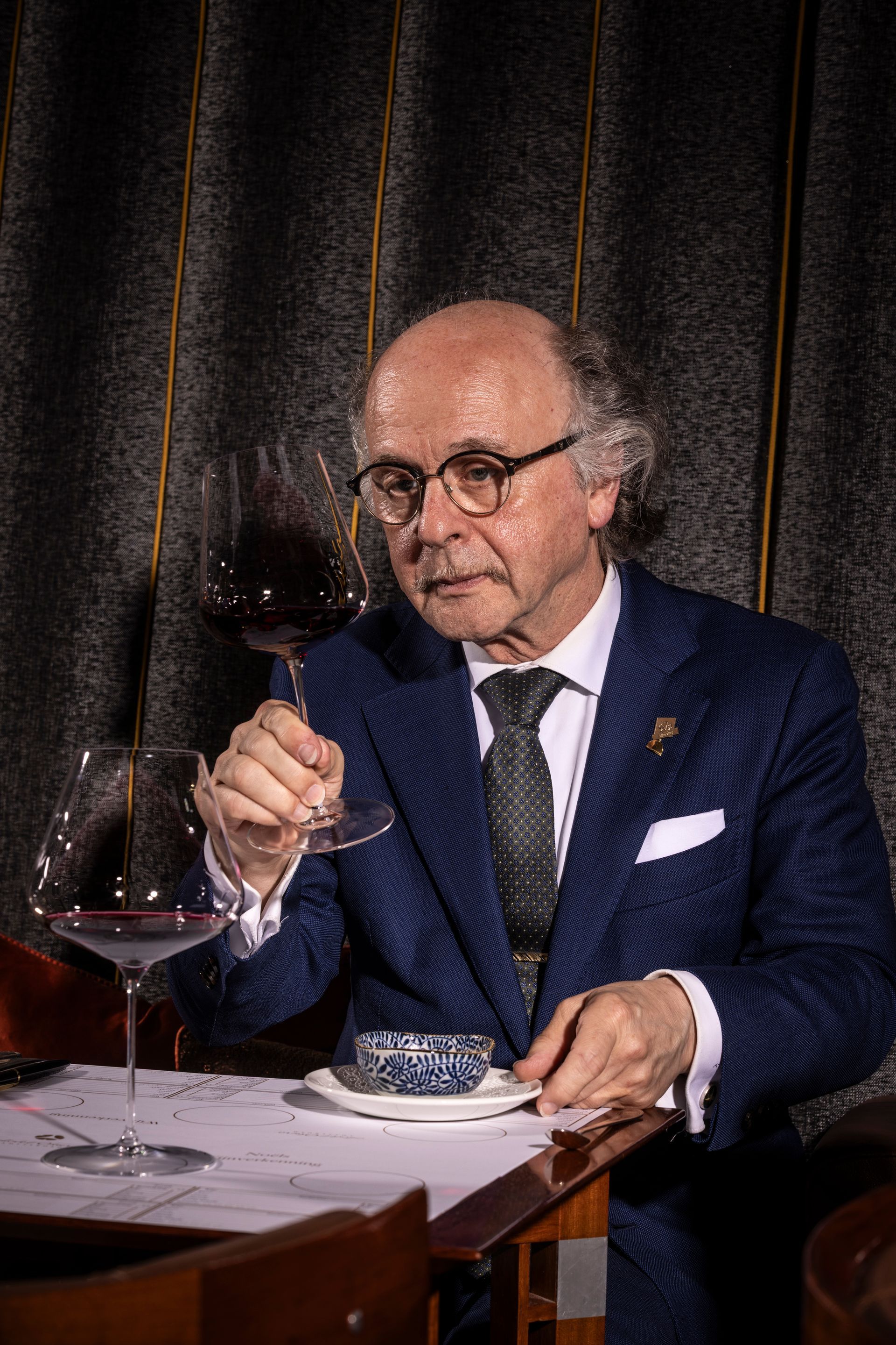 Man in suit holding a sparkling wine bottle and glass, examining its contents.