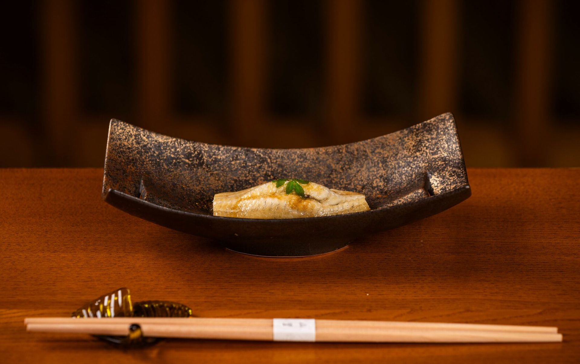 A plate of food and chopsticks on a wooden table.