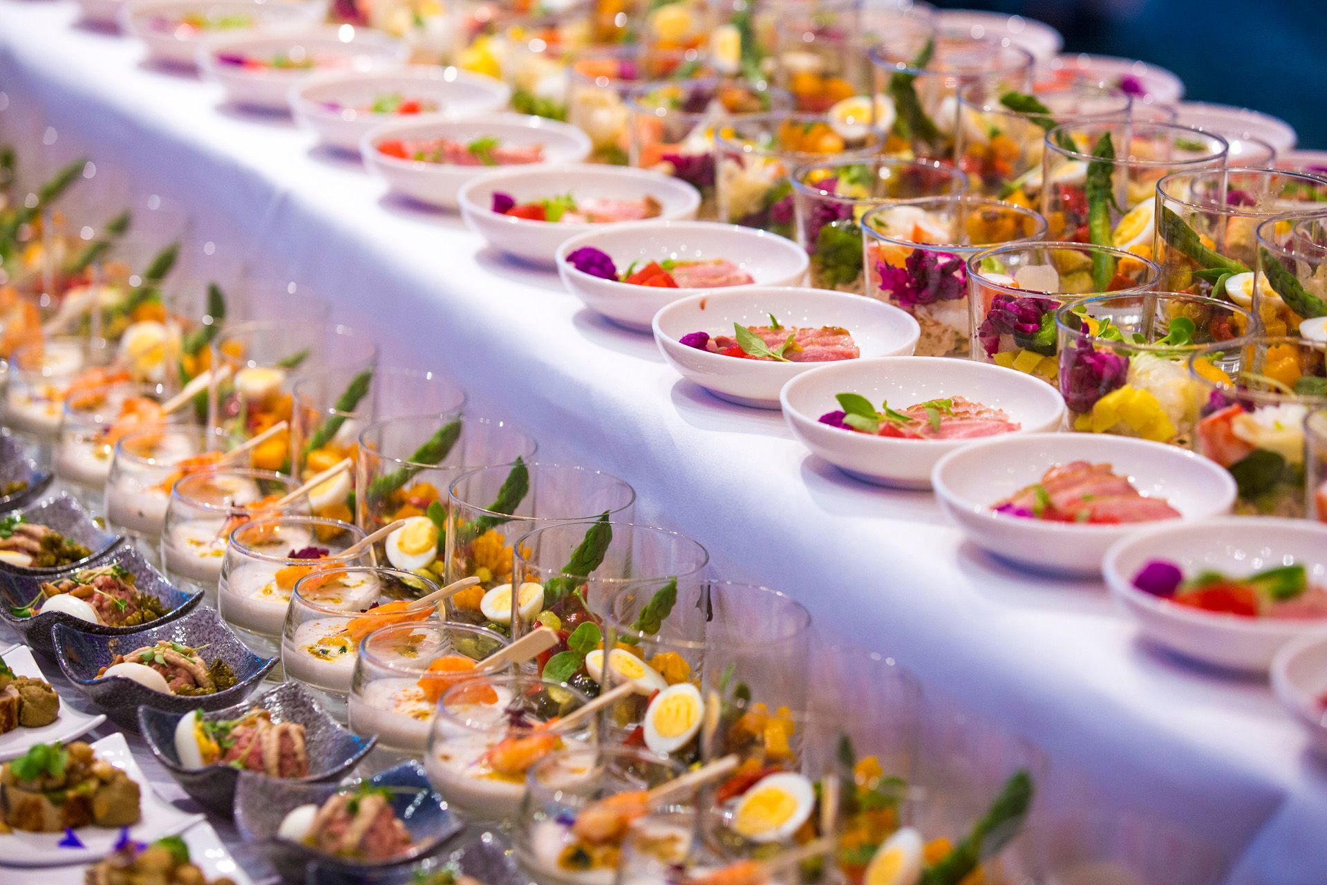 A long table topped with plates and cups of food.