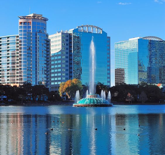 Downtown Orlando skyline with a large fountain in a lake.