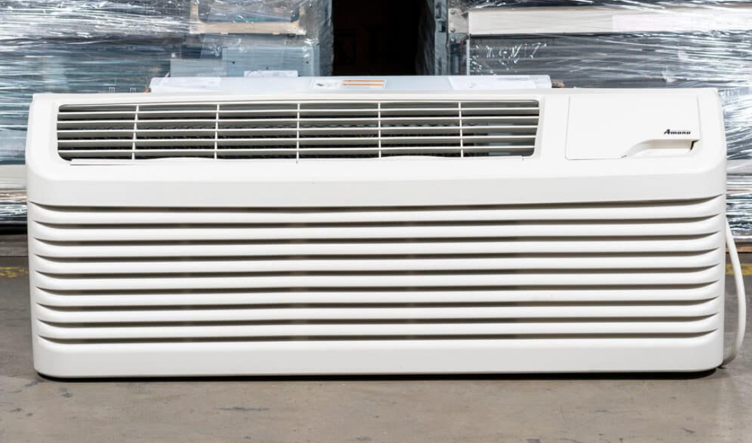 White, rectangular window air conditioner unit with horizontal slats, sitting on a floor.