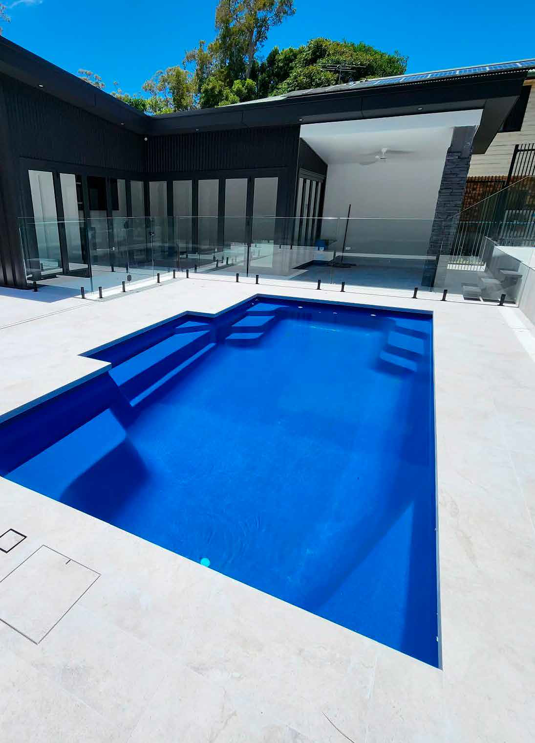 A large swimming pool is in the backyard of a house