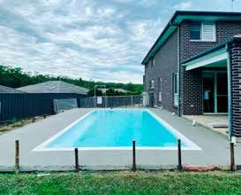 A large swimming pool is in the backyard of a house.
