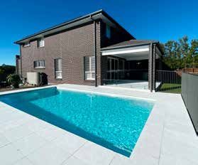 A large swimming pool in front of a large brick house.