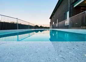 A large swimming pool surrounded by a fence in front of a house.