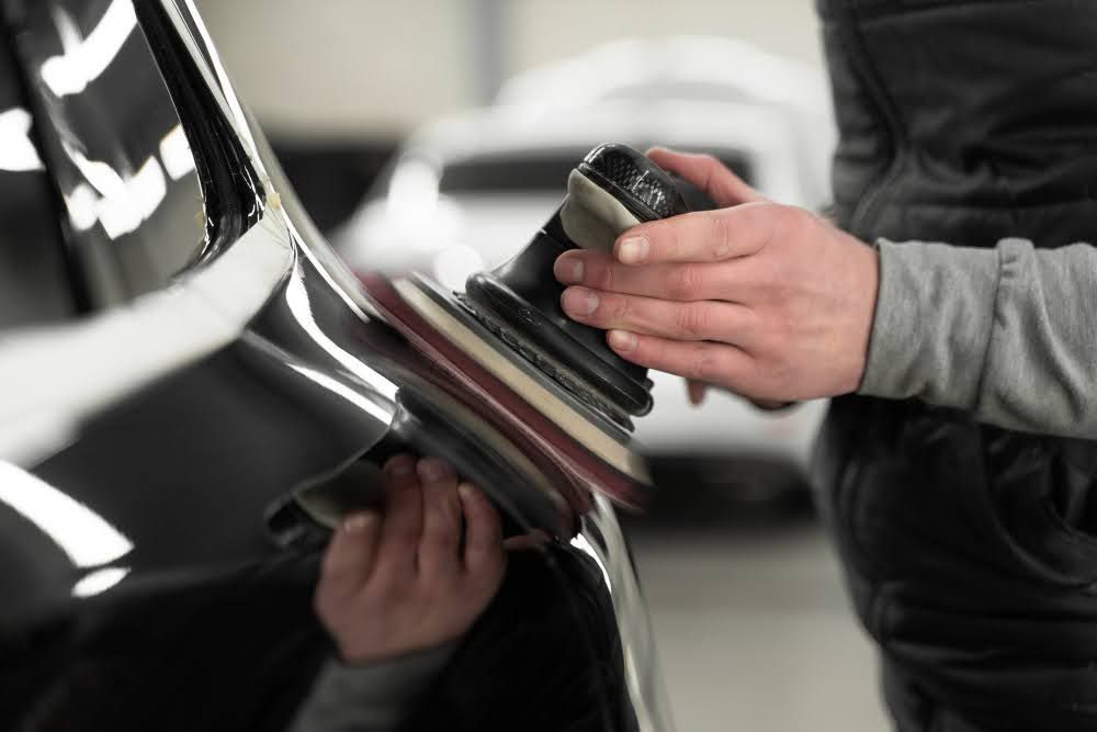 Close-up of a professional applying a layer of PPF on a car.