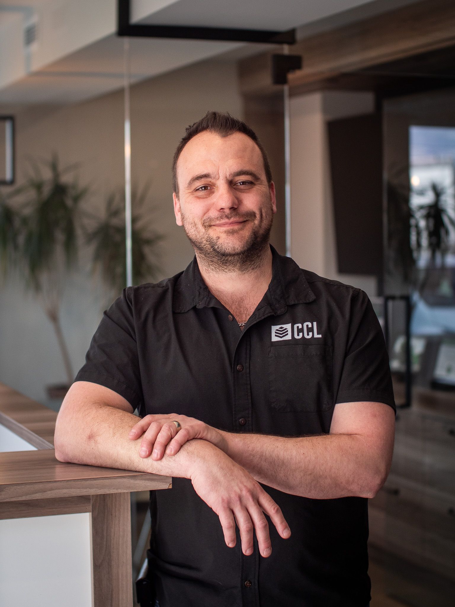 Un homme en chemise noire s'appuie sur un comptoir.