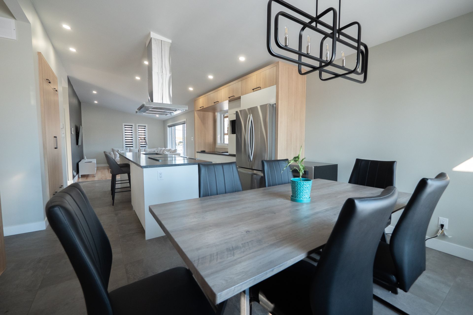 Une salle à manger avec une table et des chaises et une cuisine en arrière-plan.