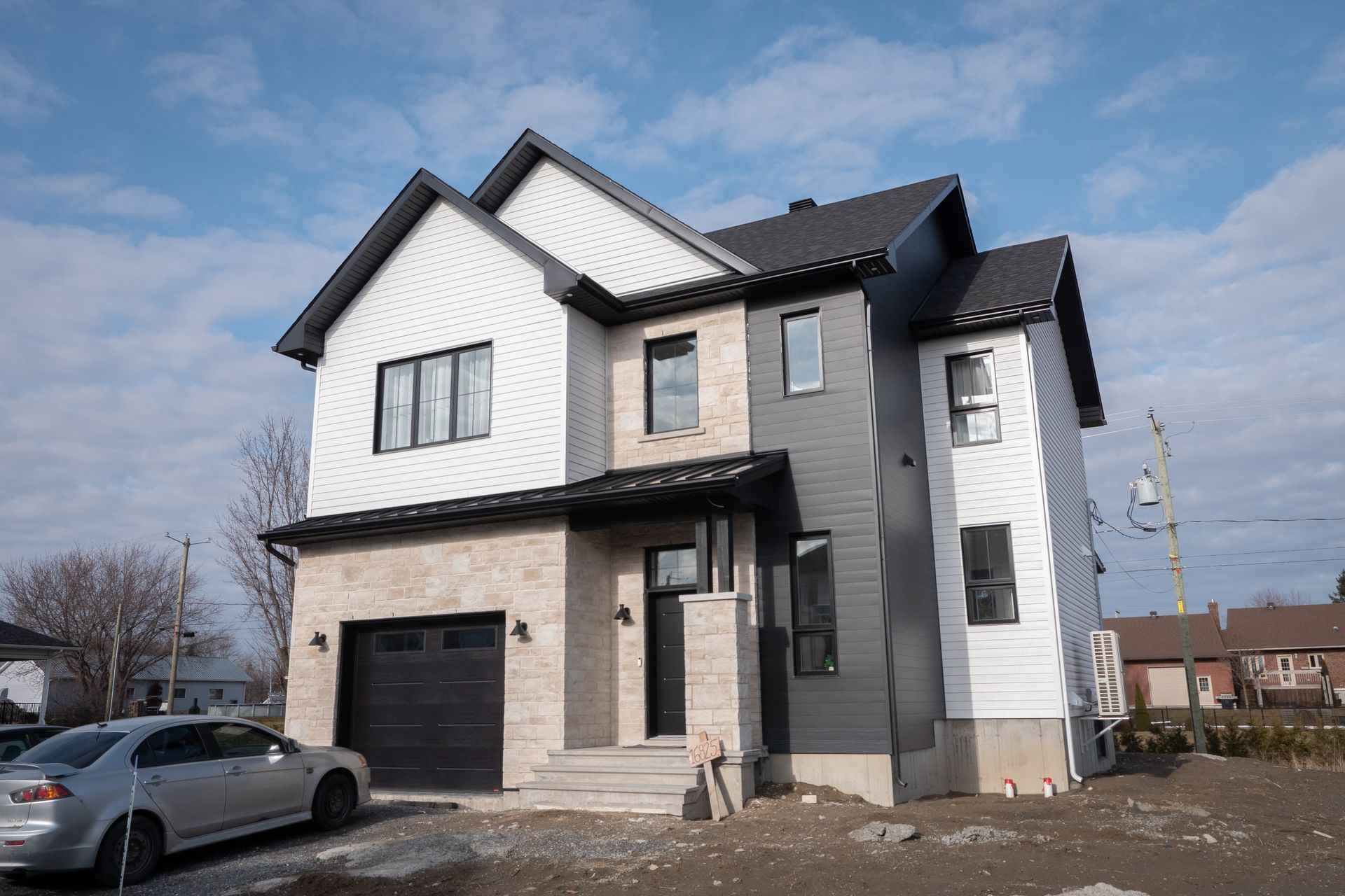 Une grande maison avec une voiture garée devant.
