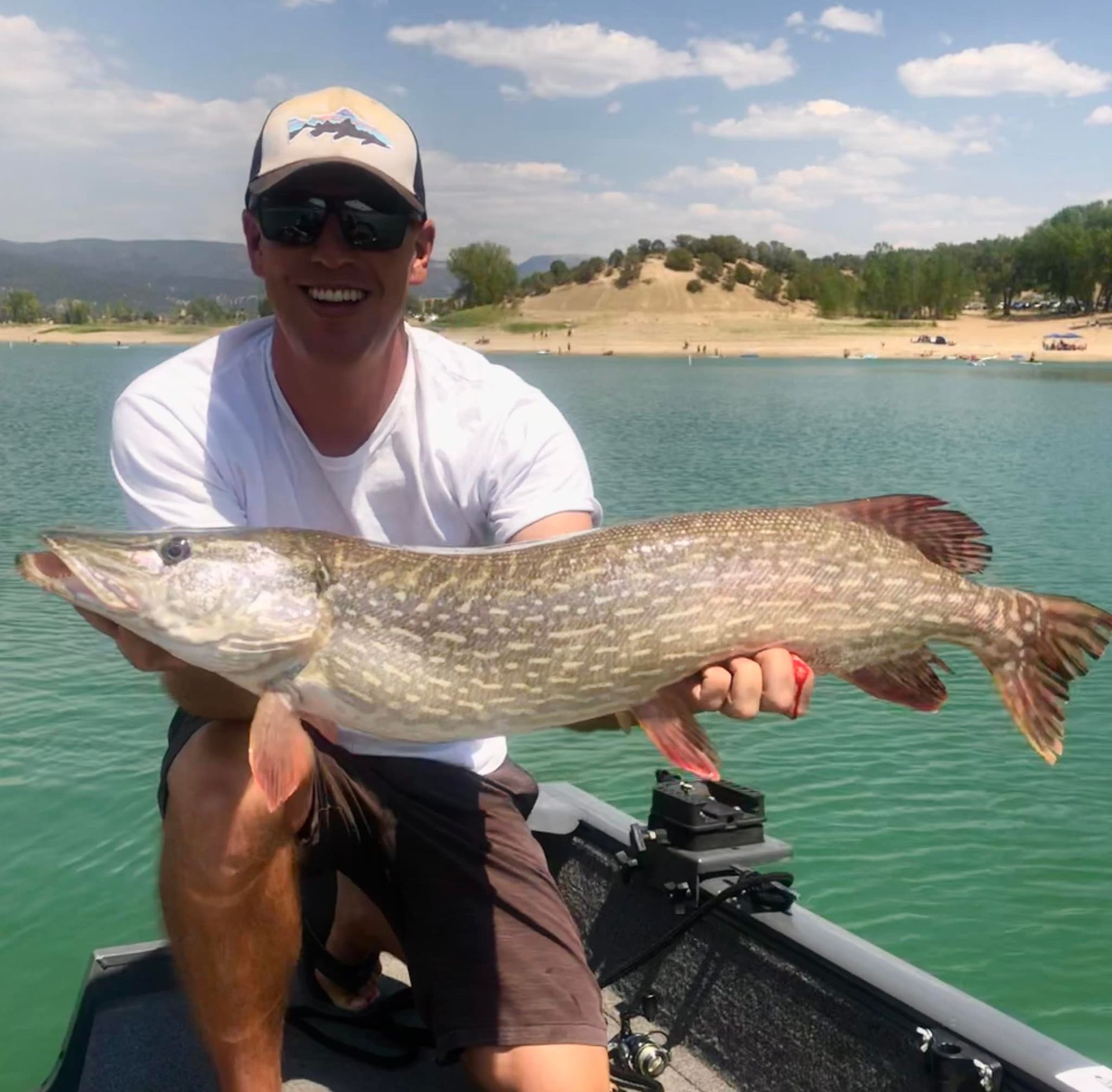 A man is sitting on a boat holding a large fish