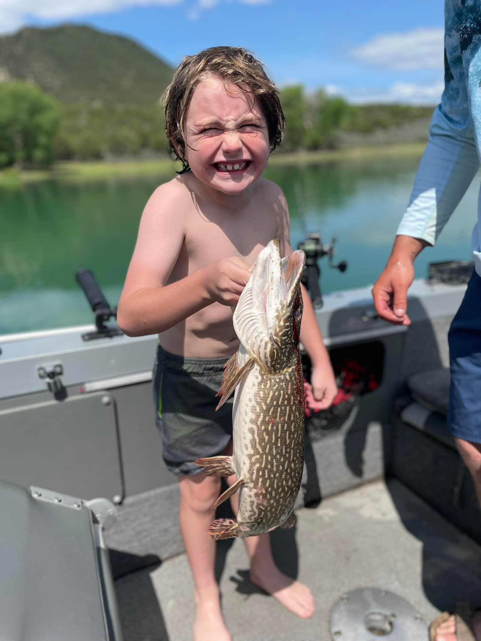 A young boy is holding a large fish on a boat.