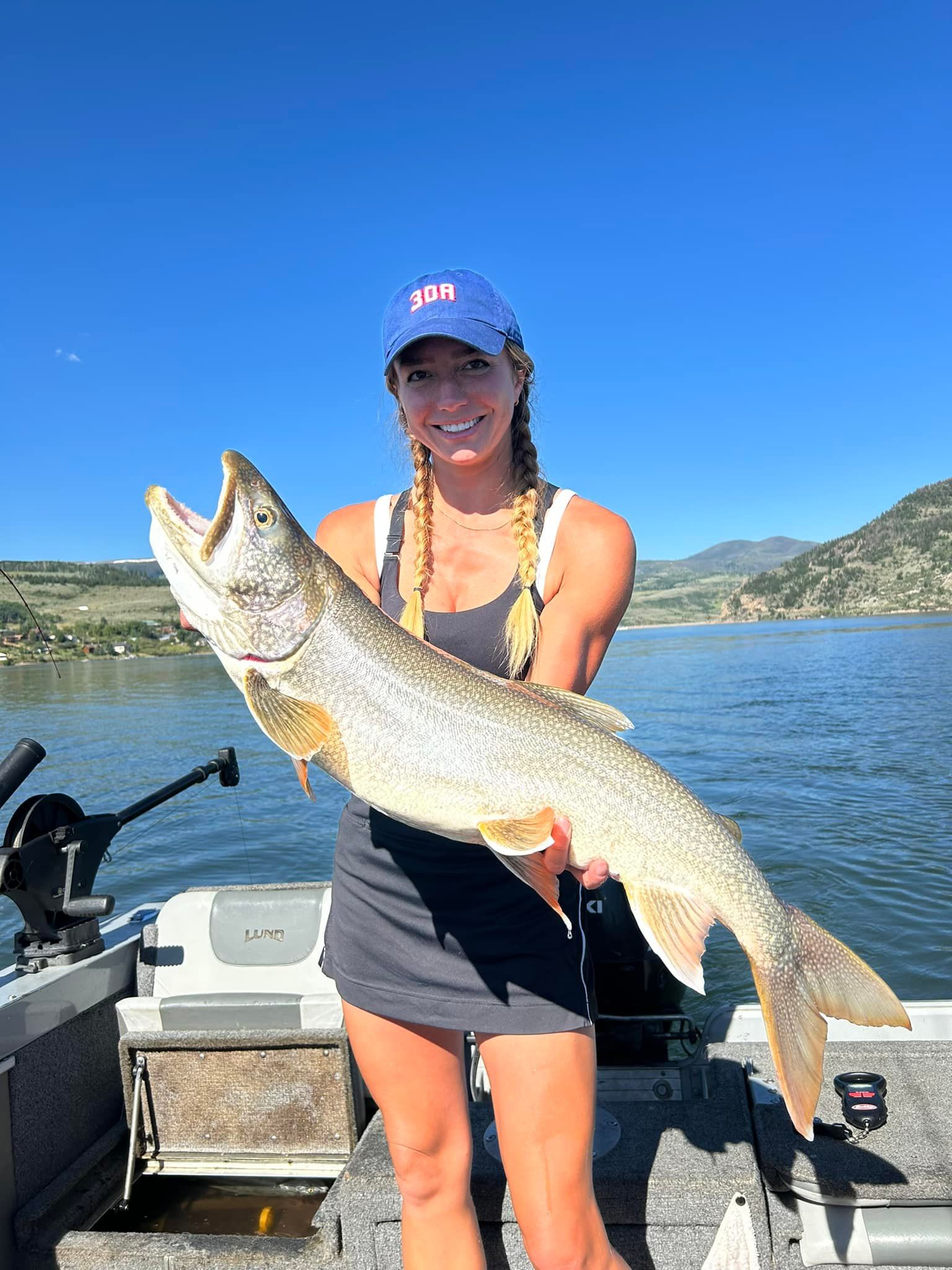 A woman is holding a large fish on a boat.