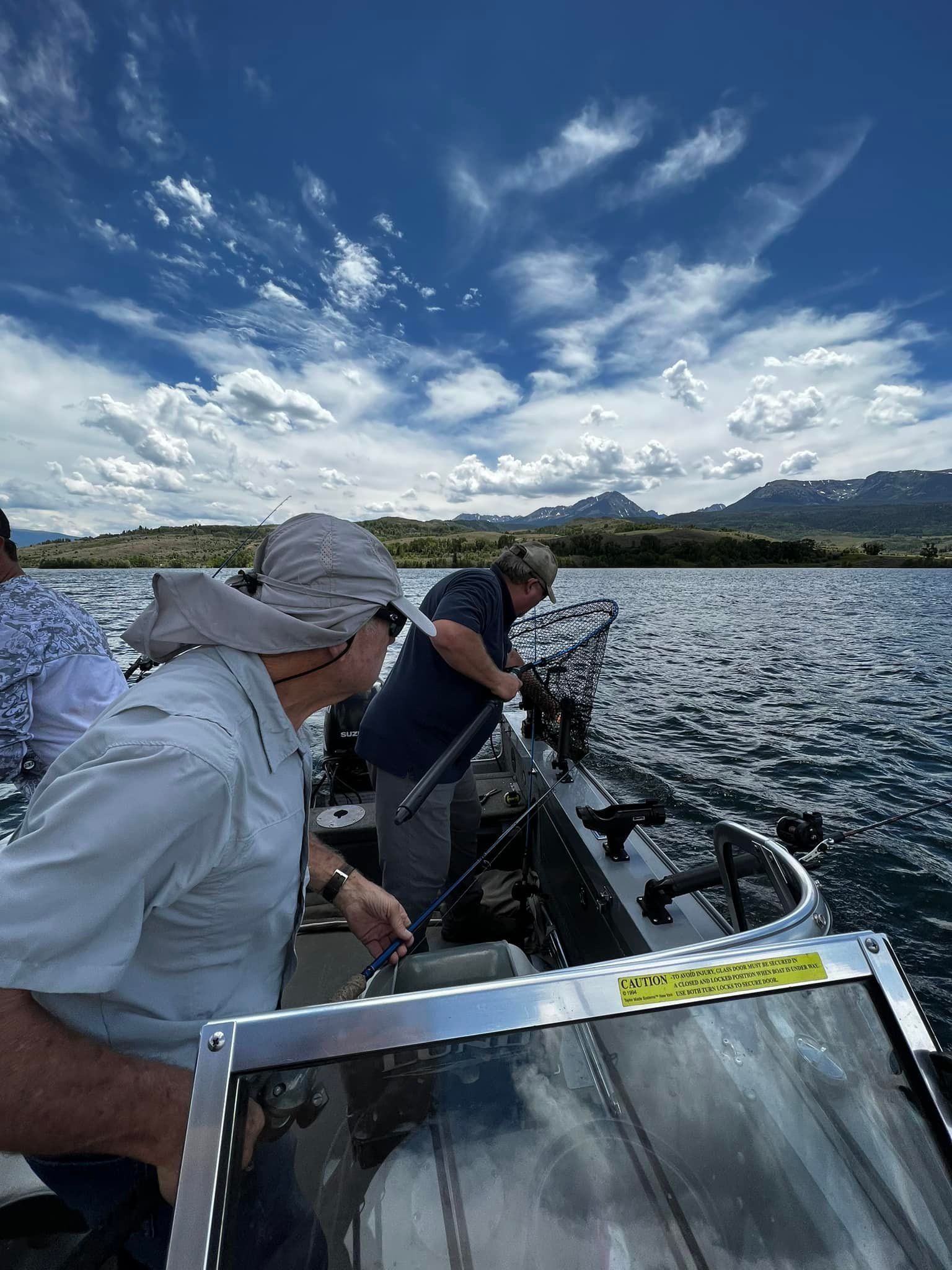 Two men are fishing in a boat on a lake.