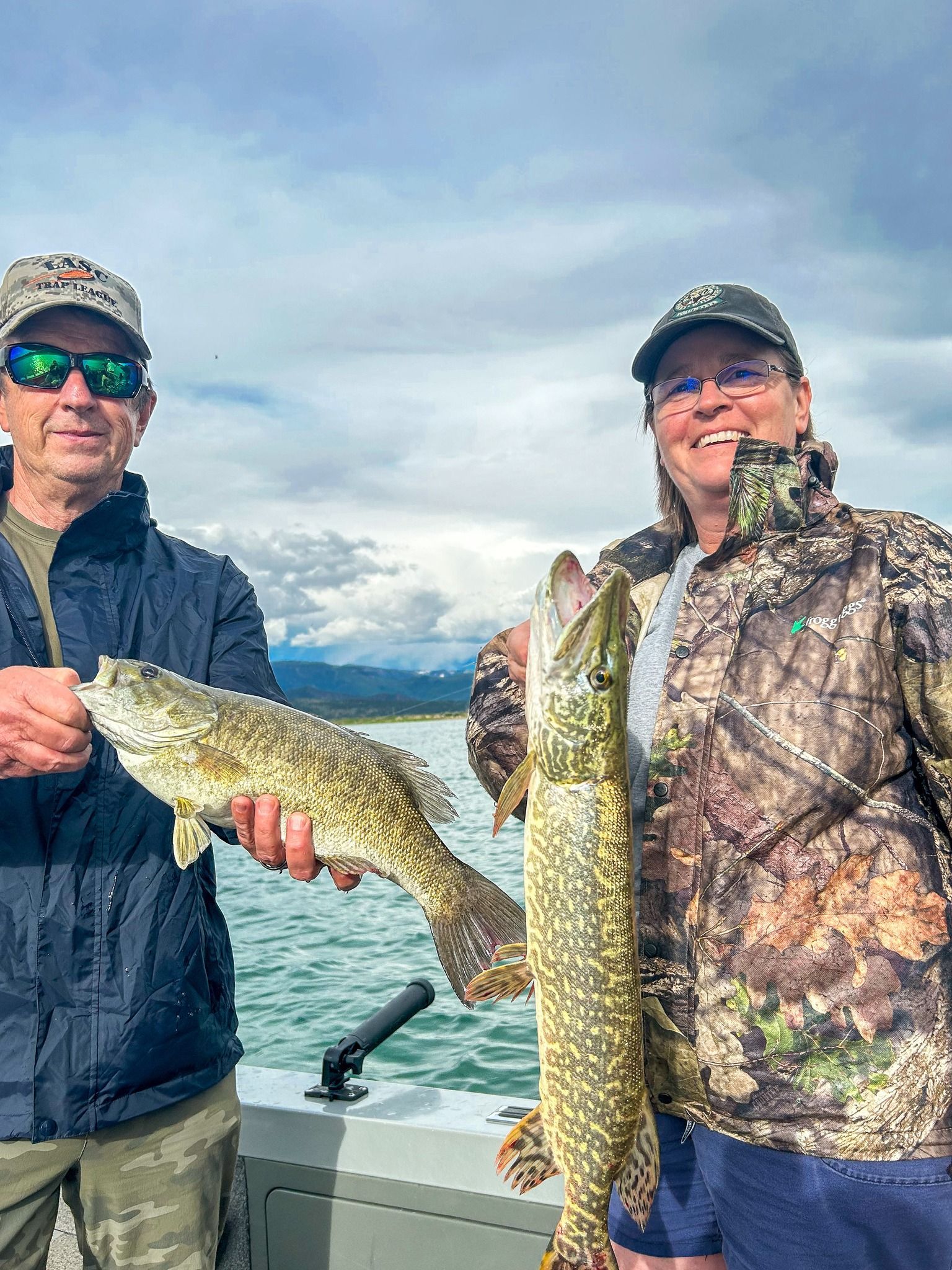 A man and a woman are holding a large fish on a boat.